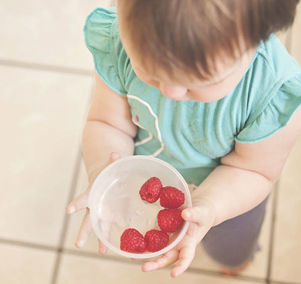 child with bowl of fruit berries