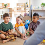 small group of preschool children sitting on the floor talking in a classroom