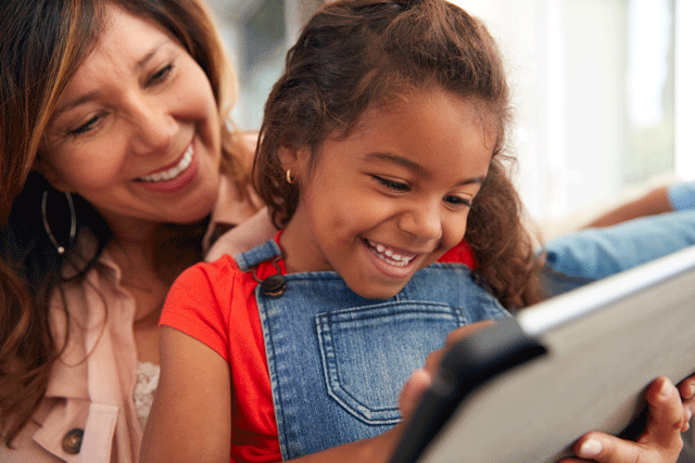 Mother and daughter smiling looking at a book