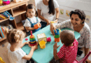 Toddlers and teachers play with blocks around a table