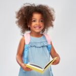 child with backpack and book