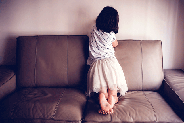 Child on the couch facing the wall