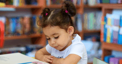 Little girl reading a book at a table
