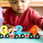 Toddler playing with cars with numbers on them