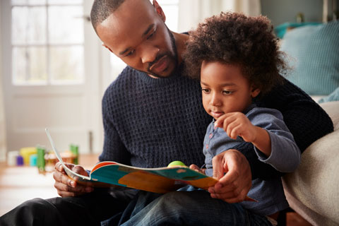 Father and child read a book together