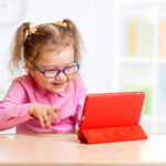 Little girl playing with a digital tablet on the countertop