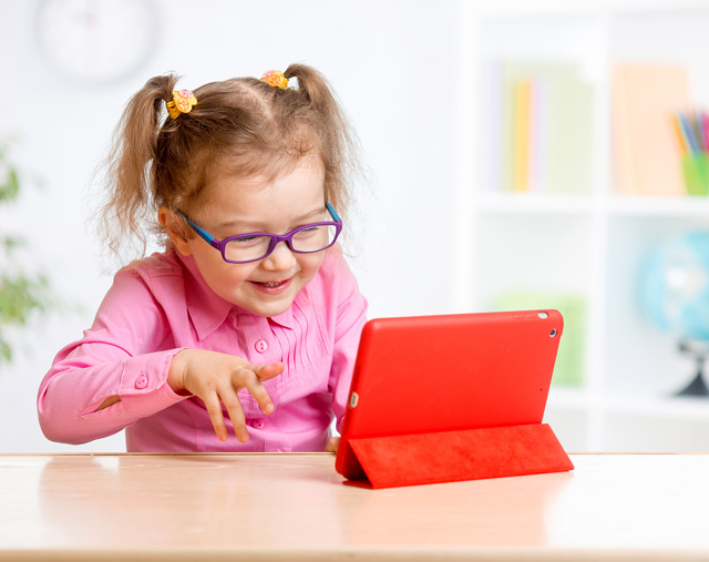Little girl playing with a digital tablet on the countertop