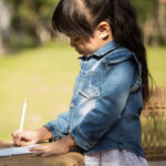 girl writing on notebook in the park