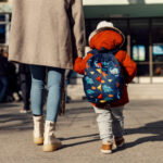kindergarten child with adult and backpack