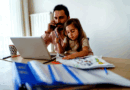 Father and daughter sit in front of a laptop