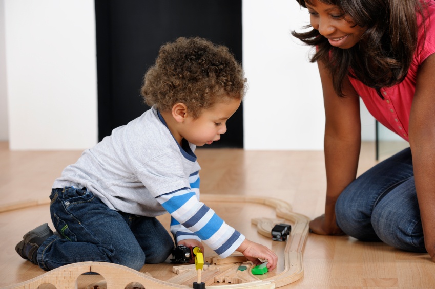 early childhood teacher watching toddler play with train