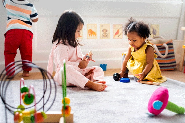 Two toddlers playing with toys on the floor