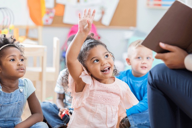 Little girl raising her hand in a classroom