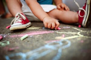 Child using chalk on the sidewalk