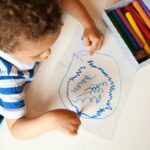 Topview of a toddler scribbling on a piece of paper