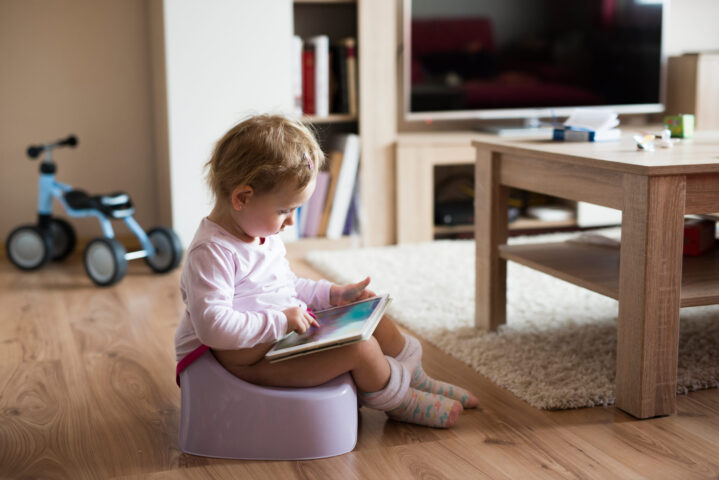 toddler at home using potty chair