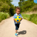 boy carrying ball outdoors