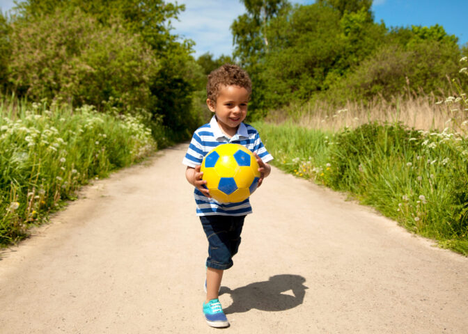 boy carrying ball outdoors