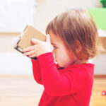 toddler girl in red shirt looking into cardboard box