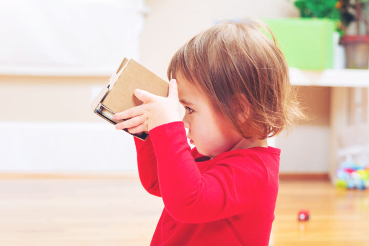 toddler girl in red shirt looking into cardboard box