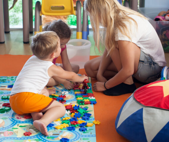two children playing with a puzzle and a parent on the floor