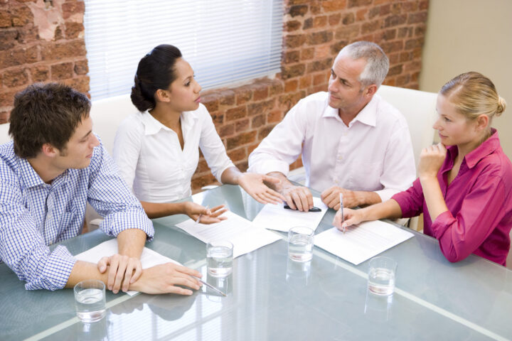 four adults sitting at a table having a meeting