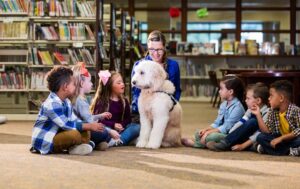children sitting in circle at library with dog