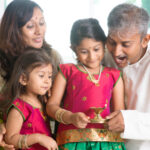 Family celebrating Diwali holding a lighted lamp