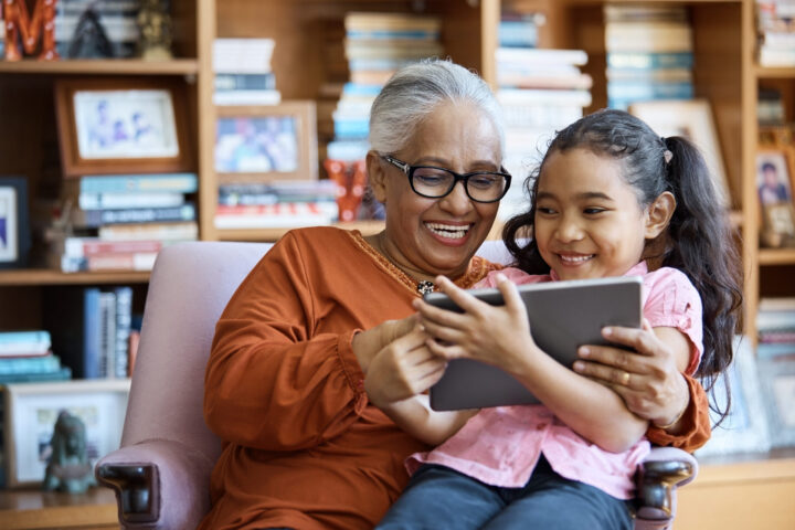 Smiling grandmother and granddaughter using digital tablet.