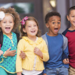 multiracial group of young children standing and laughing