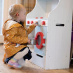 Girl with hearing aid playing with toy kitchen