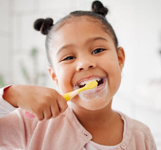 child brushing teeth in front of mirror