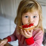 girl eating jelly on bread